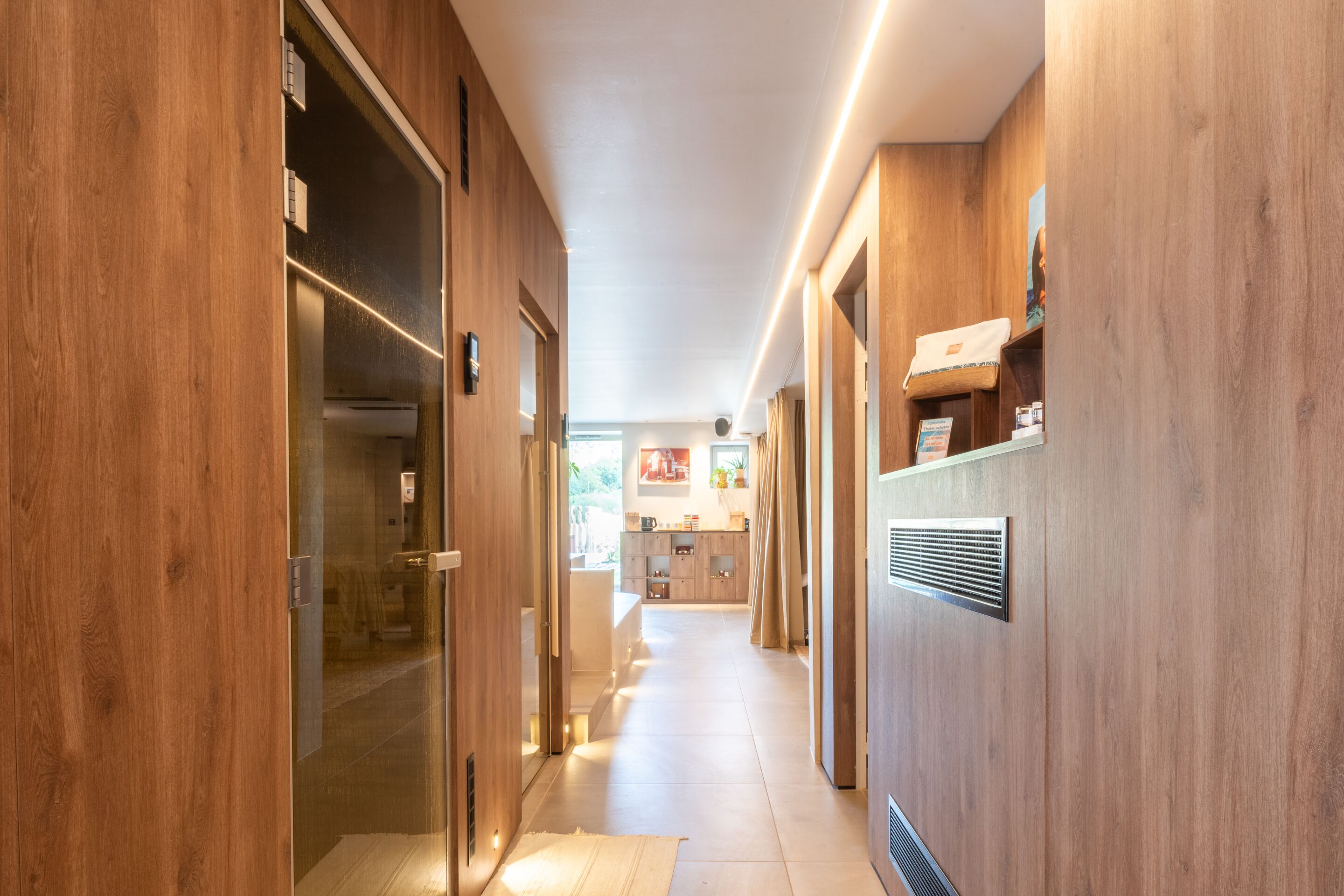 Un pasillo con paredes de madera, un vidrio y una cocina al fondo.