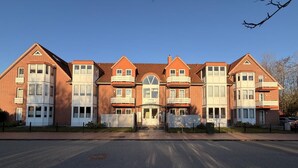 A row of red brick buildings with multiple windows and a central entrance. - Elbstrom, vacation apartment 1 (Cuxhaven)