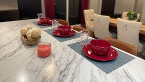 A dining table set with red plates, bowls, and a candle.