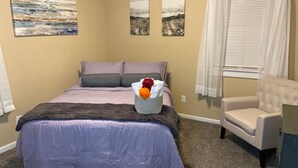 A bedroom with a bed, a chair, and three paintings on the wall.