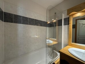 A modern bathroom with a glass-enclosed shower, a wooden vanity, and a large mirror.