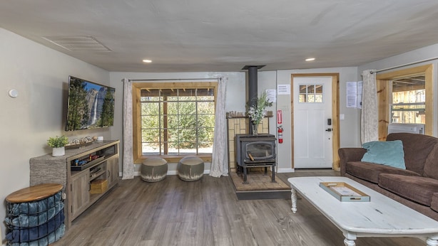 Una sala de estar acogedora con chimenea, piso de madera, un sofá, una mesa de centro y un televisor montado en la pared.