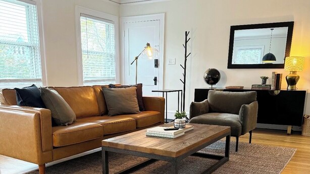 Ein modernes Wohnzimmer mit einem Ledersofa, einem Couchtisch und einer schwarzen TV-Konsole.