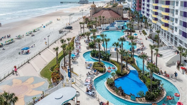 A resort with a large pool area, a beach, and a pier.