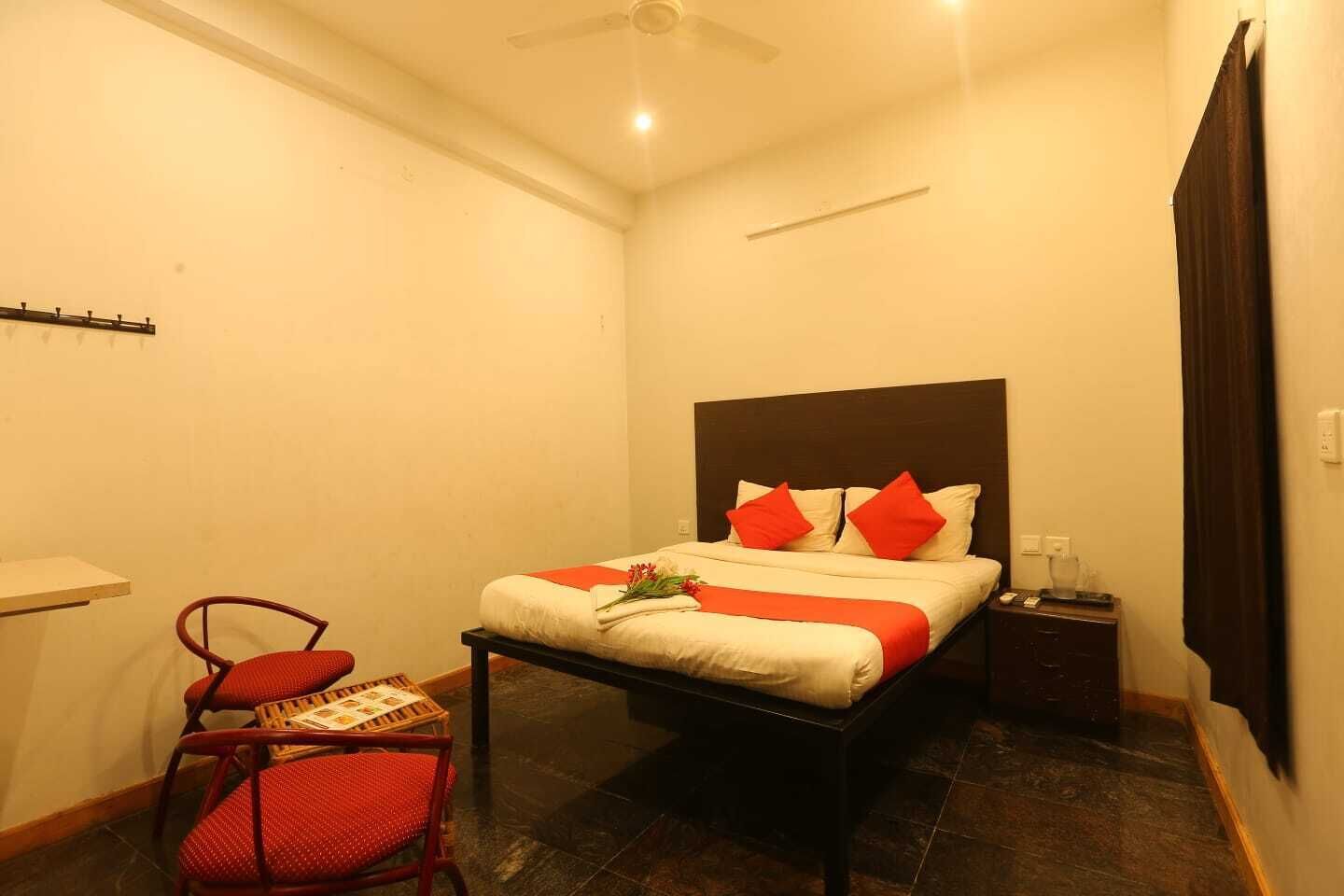 A hotel room with a bed, a chair, a nightstand, and a ceiling fan.
