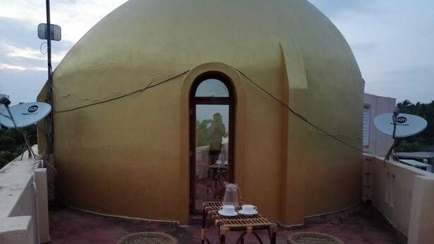 A dome-shaped building with a covered outdoor seating area featuring wicker furniture and satellite dishes. - Le Apex Guest House (Vanur)