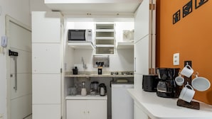 A compact kitchen with white cabinetry, a microwave, a coffee maker, and a small refrigerator. - Studio in Copacabana 5 Minutes From the Beach Nsc309 (Rio de Janeiro)
