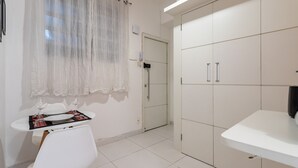 A small, clean room with a white table, two chairs, a window with sheer curtains, and a wardrobe with two doors. - Studio in Copacabana 5 Minutes From the Beach Nsc309 (Rio de Janeiro)