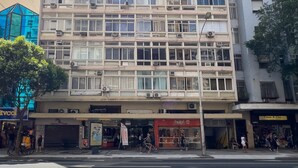 A multi-story building with a grid-like facade, air conditioning units, and a ground-level commercial area with shops. - Studio in Copacabana 5 Minutes From the Beach Nsc309 (Rio de Janeiro)
