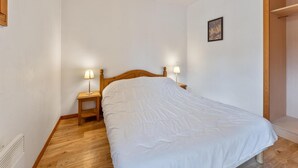 A bedroom with a wooden bed, two bedside tables with lamps, and a wooden wardrobe.