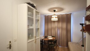 Un espacio habitable compacto con comedor, sofá y un armario con puertas de cristal.