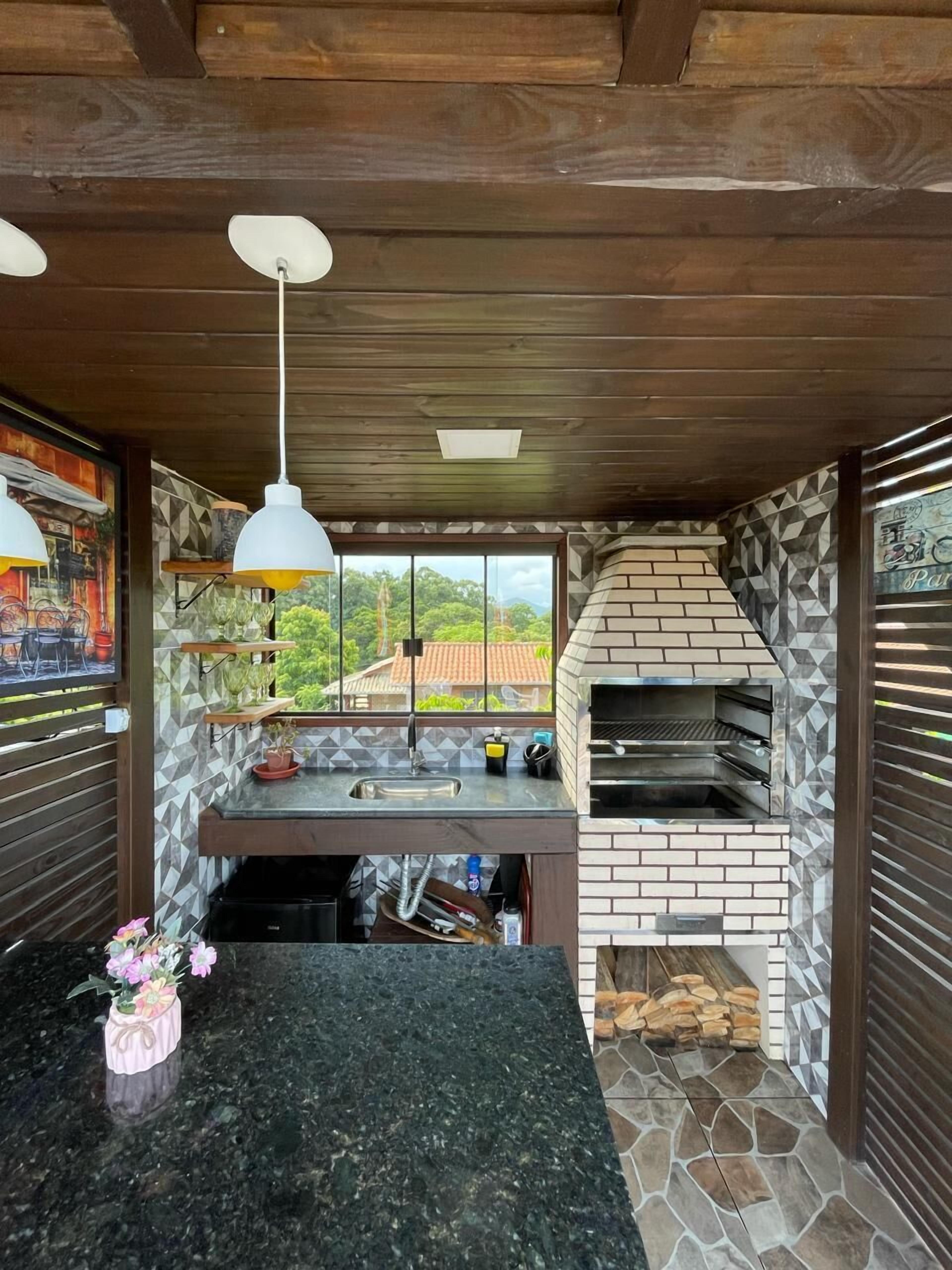 Una cocina con salpicadero de piedra, horno empotrado y ventana con vistas a un jardín.
