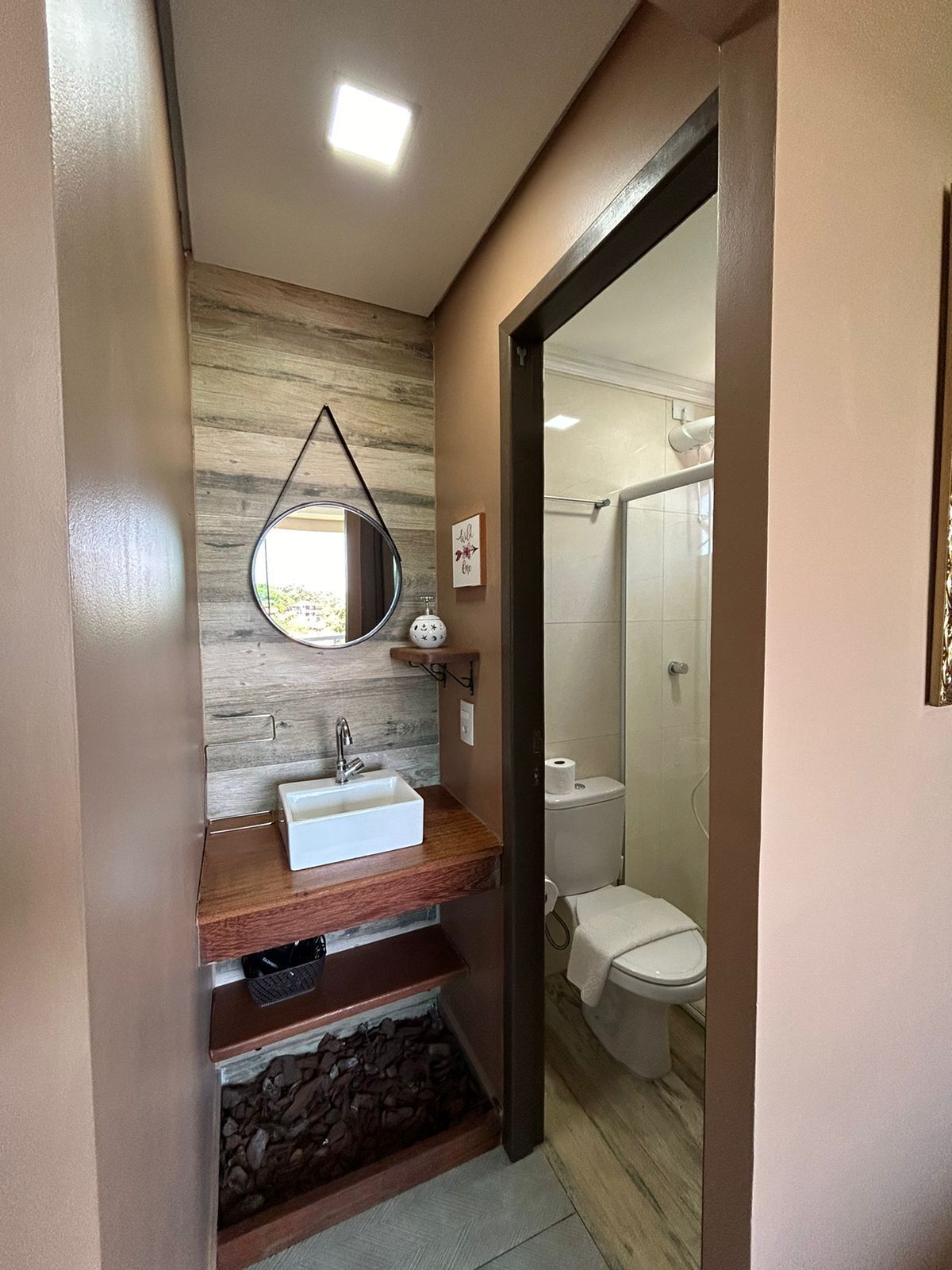 A bathroom with a wooden vanity, a sink, a mirror, and a toilet.