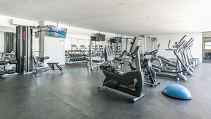 A gym with various exercise equipment, including treadmills, weight machines, and free weights.