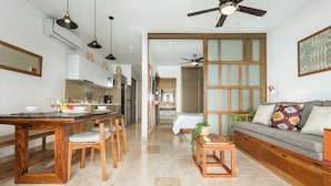 A modern kitchen with a dining area, a sofa, and a ceiling fan.
