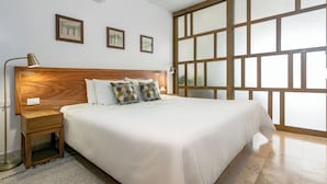 A bedroom with a large bed, wooden headboard, bedside tables, and a large window with a view.