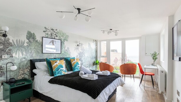 A modern bedroom with a large bed, a desk, and a chair. - Seafront Retreat: Opulent 4BR Haven for Big Groups (Birchington-on-Sea)