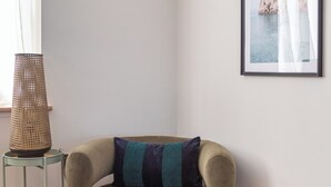A corner room with a cushioned armchair, a framed picture on the wall, a standing lamp, and a small table with a basket. - Seafront Retreat: Opulent 4BR Haven for Big Groups (Birchington-on-Sea)