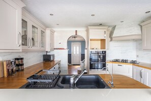 Une cuisine moderne avec des meubles blancs, un évier noir et un plan de travail en bois.
