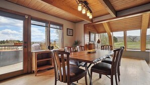 A spacious dining area with a wooden table and chairs, large windows offering a view of the countryside, and a wooden ceiling with hanging lights. - Discover your perfect getaway in this spacious 3-bedroom home in Cortez, CO!  (Cortez)