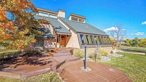 A modern house with a sloped roof, large windows, and a wooden deck. - Discover your perfect getaway in this spacious 3-bedroom home in Cortez, CO!  (Cortez)