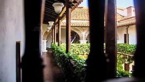 A corridor with arches and hanging lights, leading to a courtyard with plants and a building with a tiled roof. - Spacious 9-bedroom apartment with WiFi, AC in awesome Cartagena (Cartagena)