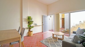 A spacious living area with a dining table, chairs, a sofa, and a coffee table. There is a potted plant and a rug on the floor. - Colorful Zen APTs 2 Blocks to the Beach (La Paz)