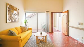 A living room with a yellow sofa, a round coffee table, and a Buddha painting on the wall. - Colorful Zen APTs 2 Blocks to the Beach (La Paz)