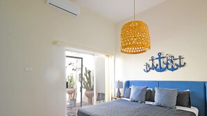 A bedroom with a large bed, a blue headboard, a hanging lamp, and a wall-mounted anchor decoration. - Colorful Zen APTs 2 Blocks to the Beach (La Paz)