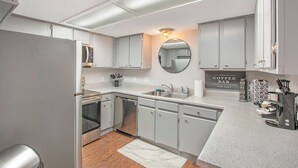 Een moderne keuken met roestvrijstalen apparatuur, een koffiebar en een ronde spiegel.