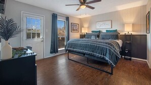 Een slaapkamer met een bed, een plafondventilator, een raam met gordijnen en een deur.