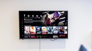 A television mounted on a wall displaying a Netflix interface with various shows and movies.