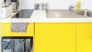 A kitchen with yellow cabinets, a stainless steel sink, a toaster, a coffee maker, and a microwave. - Immaculate Studio Apartment in Sheffield City (Sheffield)