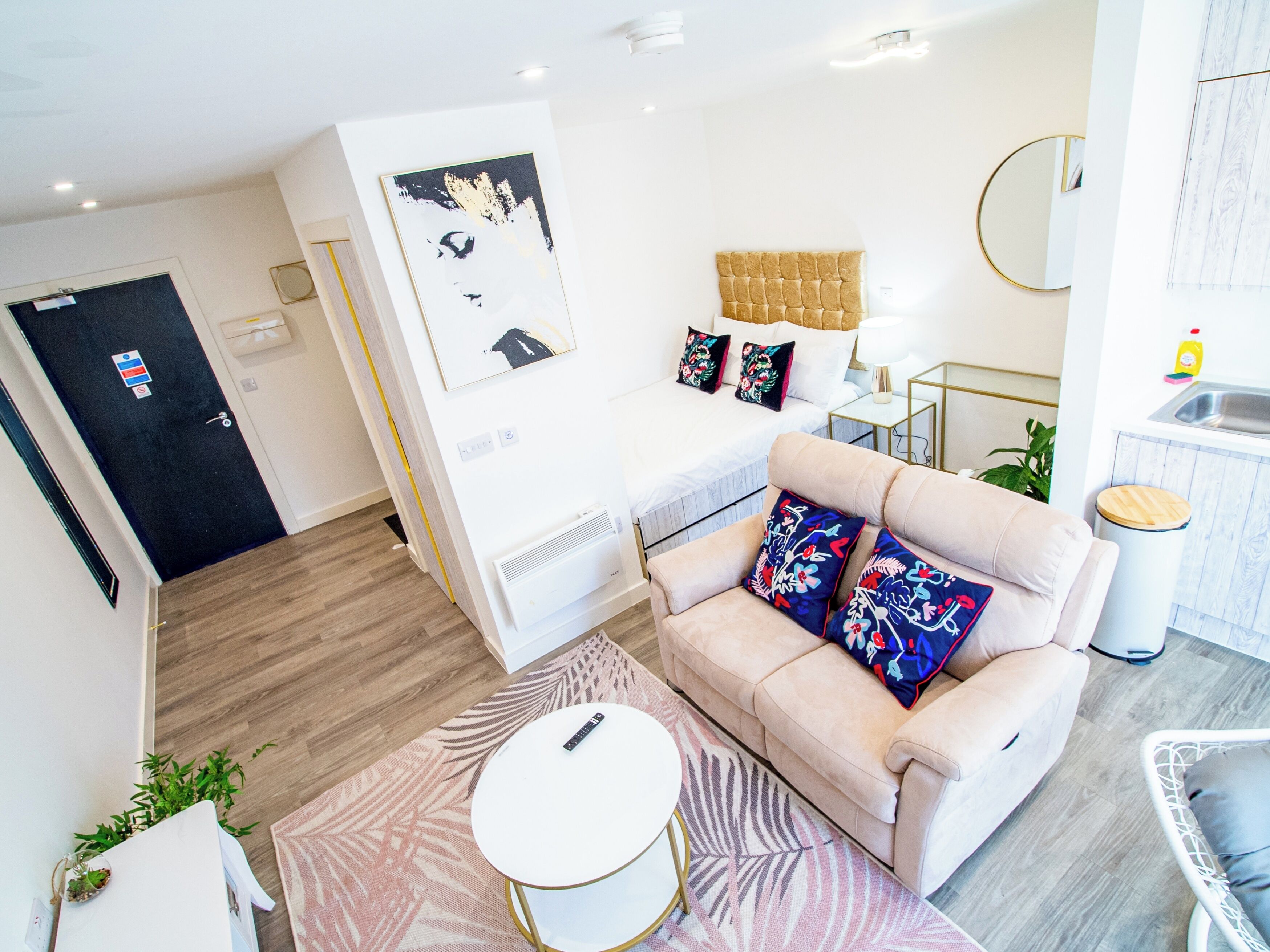 A modern living room with a sofa, a small round table, and a bed with a headboard.