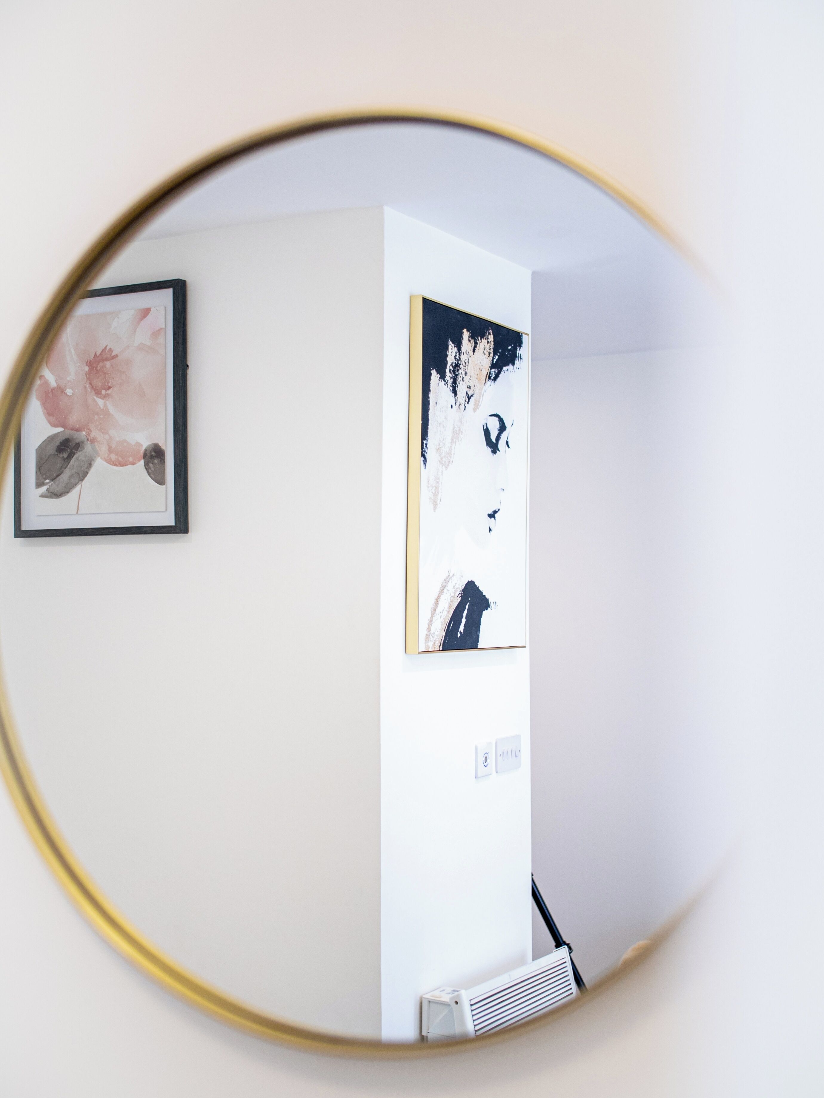 A room with a white wall, a framed artwork, and a white radiator.