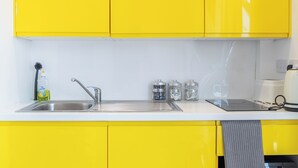 A kitchen with yellow cabinets, a stainless steel sink, and a coffee maker. - Deluxe Studio Apartment by Sheffield City Centre (Sheffield)