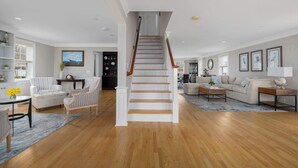 Un vaste espace de vie comprenant un escalier, un plancher en bois et un assortiment de meubles, notamment des canapés et une table basse.