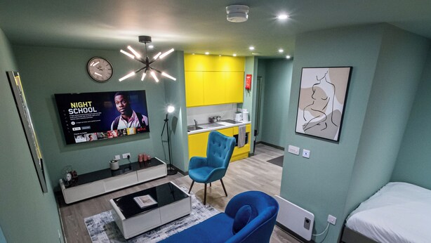 A modern, compact living space with a TV, sofa, and kitchenette. - Central Sheffield City Apartment (Sheffield)