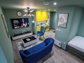 Een moderne, compacte leefruimte met televisie, bank en kitchenette.