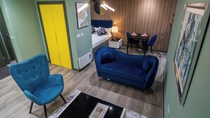 A compact hotel room with a bed, a desk, a chair, a blue sofa, and a small table. - Central Sheffield City Apartment (Sheffield)