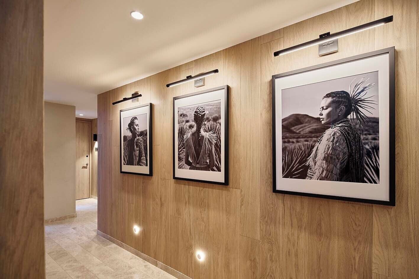 A hallway with framed black and white photographs on the wall.