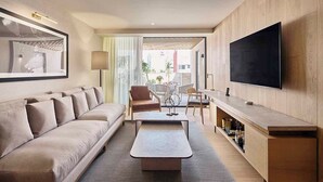 Ein modernes Wohnzimmer mit Sofa, Couchtisch, Fernseher und einem Essbereich mit Stühlen und Tisch.