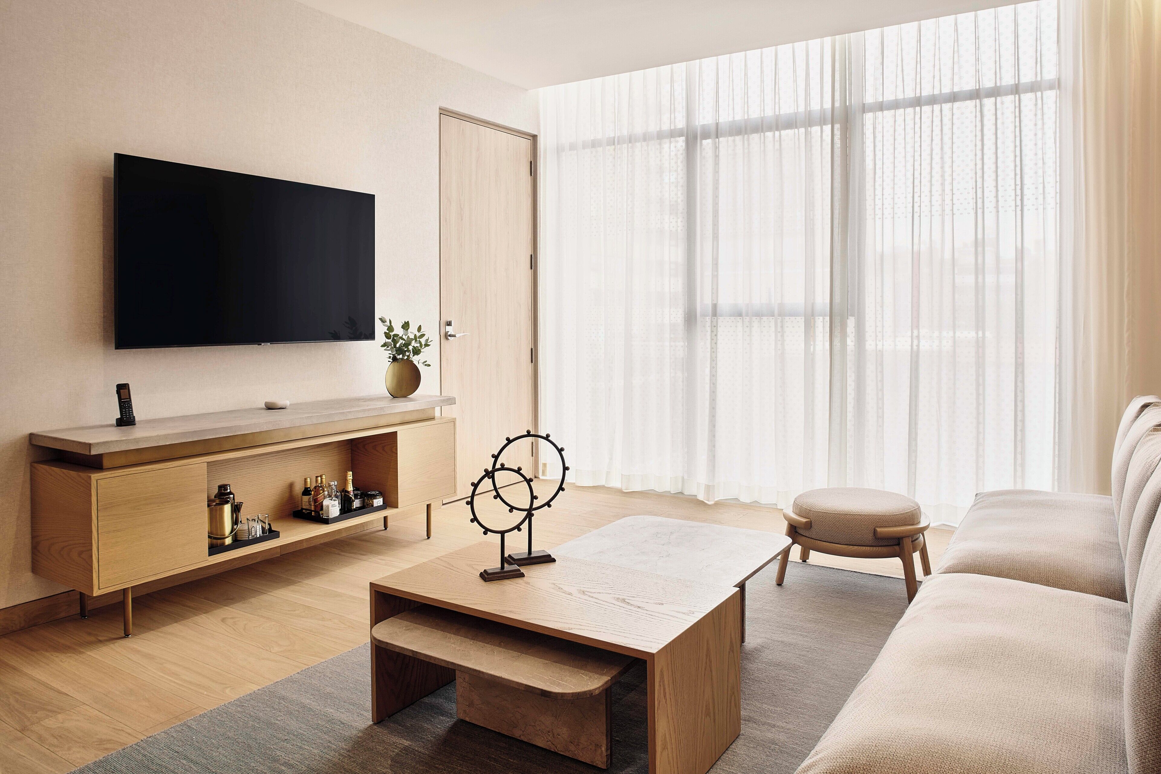 A modern living room with a flat-screen TV, wooden coffee table, and a sofa.
