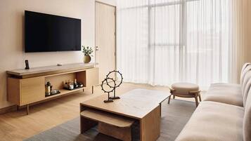 A modern living room with a flat-screen TV, wooden coffee table, and a sofa.