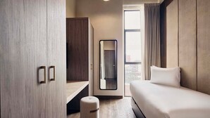 Ein modernes Hotelzimmer mit Bett, Schreibtisch und Kleiderschrank.