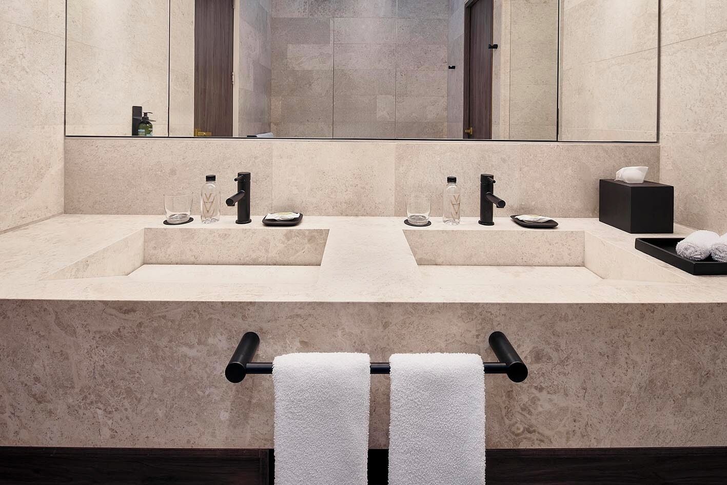 Un baño moderno con dos lavamanos, un espejo grande y un perchero para toallas.