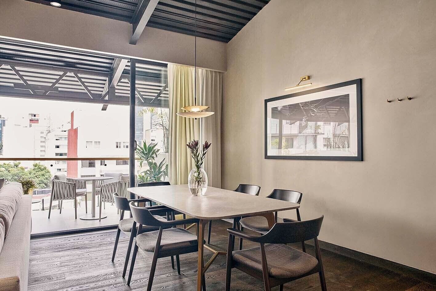A modern dining area with a large table, chairs, and a vase of flowers.