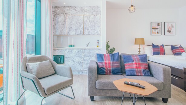 Un salon moderne avec un canapé gris, une petite table basse et une télécommande posée dessus.