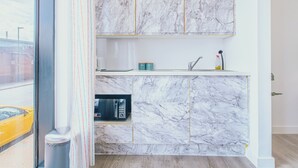 Une cuisine moderne dotée de plans de travail en marbre et d’éléments décoratifs dorés, comprenant un four à micro-ondes encastré et un évier.