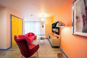 A modern living room with a red sofa, a small coffee table, a TV, and a chandelier. - Outstanding Deluxe Self Contained City Apartment (Sheffield)